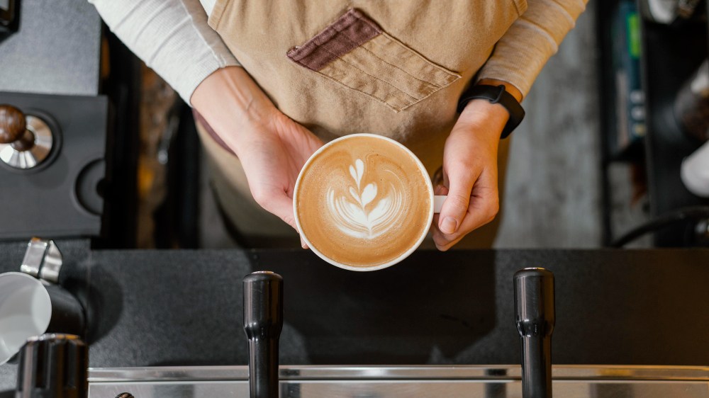 Vue de dessus d'une femme barista tenant une tasse de café