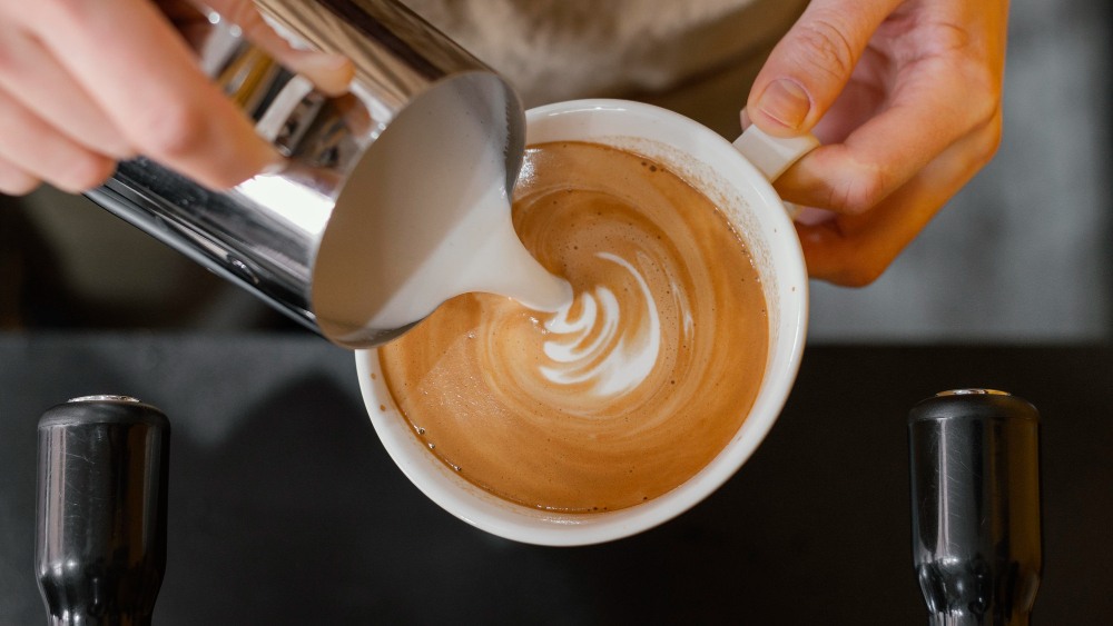 Vue de dessus du barista masculin verser du lait dans des tasses à café