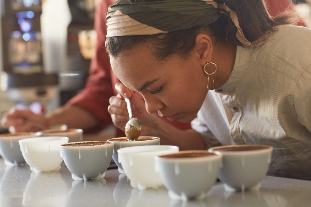 Portrait de côté d'une jeune femme sentant du café lors d'un test de qualité et de dégustation dans un café