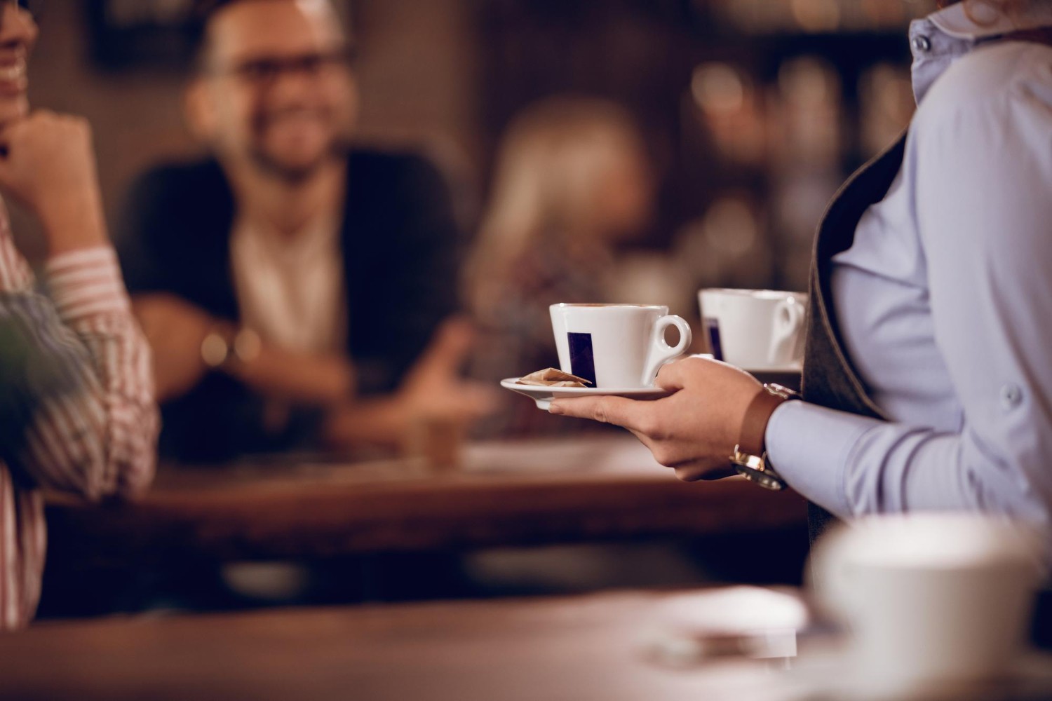 Gros plan d'une serveuse transportant des tasses de café dans un café