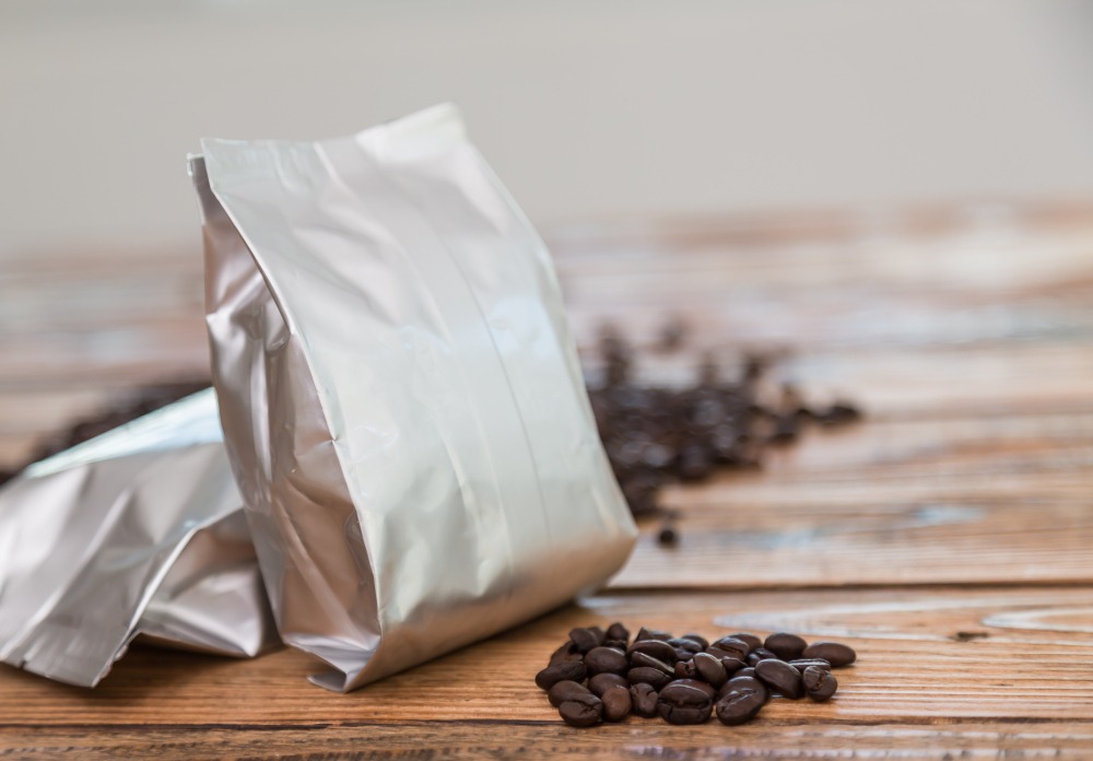 sac à café métallique avec des grains de café derrière